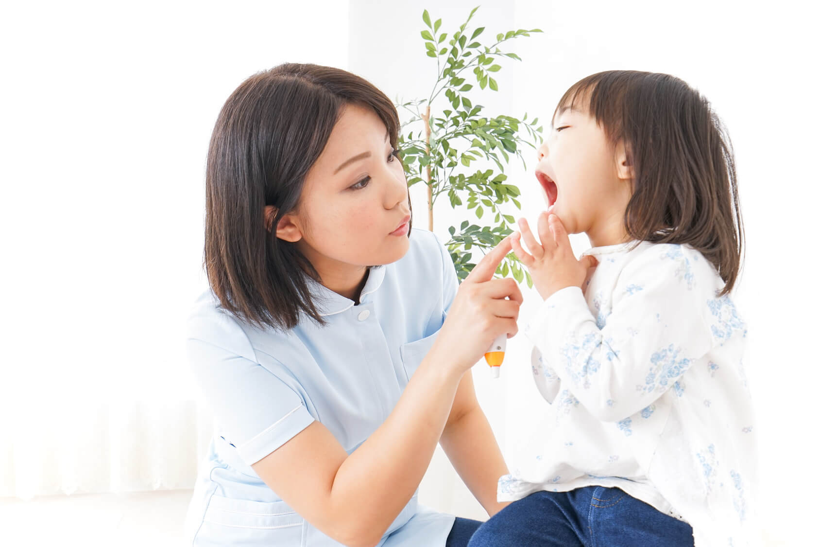 医師が子供の口の中を見ている写真